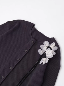 Close-up of dark grey ribbed knit cardigan featuring white organza floral applique and ribbons