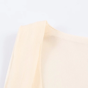 Detalle macro de la costura del hombro y el escote en tela de gasa beige de calidad
