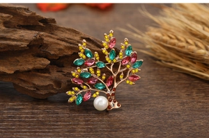 Macro detail of Tree of Life brooch featuring colorful crystals and a large pearl inlay