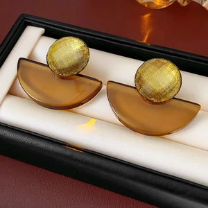 Close-up of geometric resin earrings in amber brown with gold glitter stud on a jewelry box