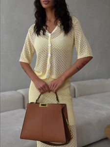 Detail view of yellow crochet knit texture and white buttons on a stylish two-piece skirt set