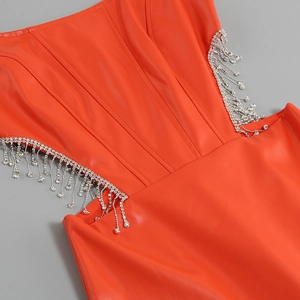Détail de la robe en cuir PU orange avec franges en strass et découpe latérale élégante