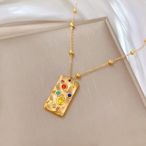 Detailed view of gold beaded chain necklace with multi-colored gemstone square pendant