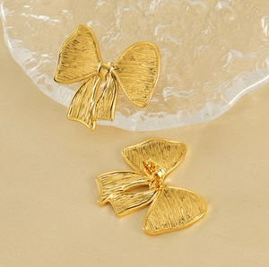 Gros plan de boucles d'oreilles nœud plaquées or 18K avec une texture en métal brossé