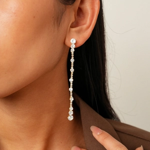 Close-up of elegant gold tassel earrings with zircon stones on a model ear