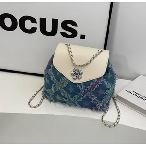 Detail of blue denim chain bag with white leather flap and silver flower ornament