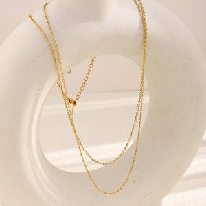 Detailed view of layered 18K gold plated stainless steel O-chain on a white ceramic vase