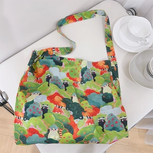 Detailed close-up of cotton crossbody bag with green forest and cat prints on white table