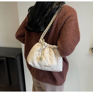 Detailed view of white quilted bucket bag with elegant gold chain strap and gathered texture