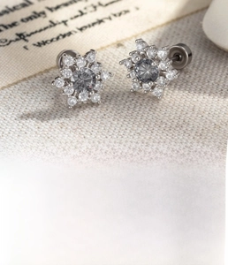 Macro detail of silver snowflake cartilage piercing made of titanium steel and cubic zirconia