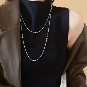 Silver double-layer snake chain necklace with beads styled on a black turtleneck sweater