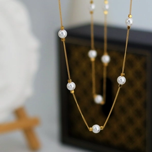 Elegant gold necklace with five white pearls and geometric beads on thin steel chain