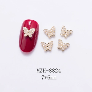 Detailed view of 7x6mm golden mini butterfly nail charms with pearls on red nails