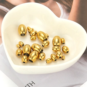 Golden stainless steel oval spacer beads in various sizes displayed on a ceramic plate