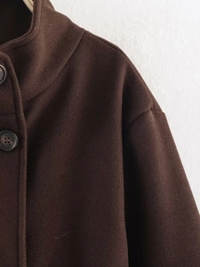 Detail view of the stand collar and round resin buttons on a dark brown wool coat