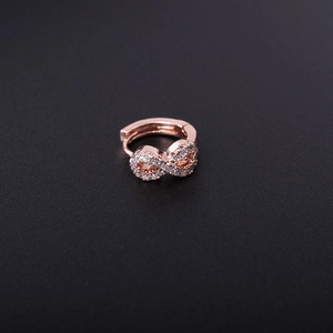 Macro view of rose gold infinity huggie hoop earring with clear cubic zirconia stones