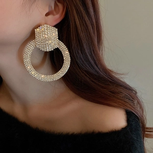 Close-up of model wearing large gold-tone round earrings with sparkling crystals