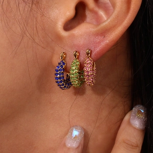 Close-up of C-shaped gold hoop earrings with multi-colored pavé cubic zirconia inlay