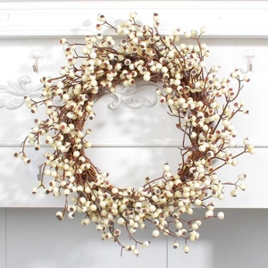 Christmas wreath with cream white berries and dark brown twigs on a white wall