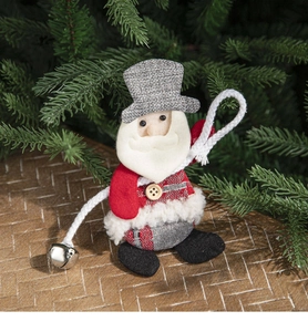 Detail of plush Santa ornament with grey hat and silver bell on a festive pine background