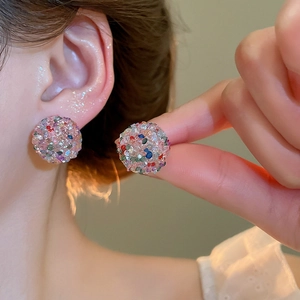 Detail showing colorful crystal encrusted ball stud earrings worn on the earlobe