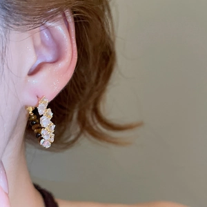 Macro shot of 18k gold plated C-shape hoop earring with tiger eye stone and zircons