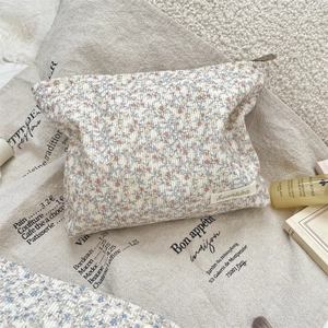 Detailed close-up of corduroy floral makeup bag with metal zipper and brand label