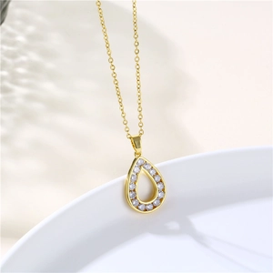 Macro shot of gold teardrop pendant with clear cubic zirconia pavé and hollow center