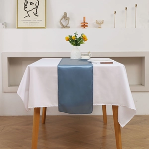 Close-up of royal blue satin table runner with smooth silky texture on a white tablecloth