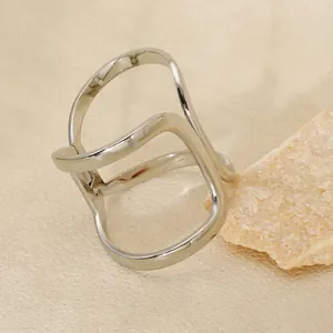Polished silver geometric hollow wavy stainless steel ring displayed on a mineral stone