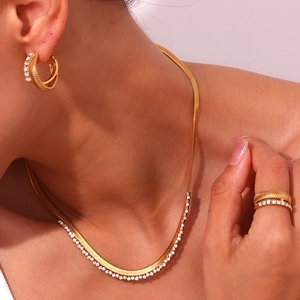 Detail of 18K gold plated herringbone chain necklace and rhinestone jewelry set on model
