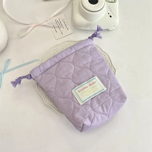 Quilted lavender drawstring pouch detail on a white ceramic plate for camera storage