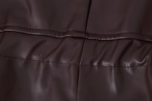 Detailed macro view of deep brown quilted faux leather texture with reinforced stitching