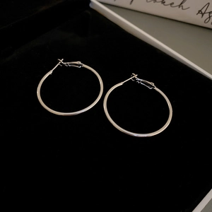 Macro shot of silver minimalist hoop earrings on a black velvet jewelry display tray