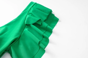 Detailed macro view of multi-layered ruffles on emerald green swimsuit fabric