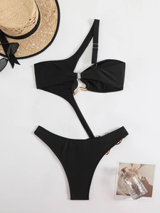 Flat lay of a black one-shoulder cutout swimsuit with gold metal ring detail on white background
