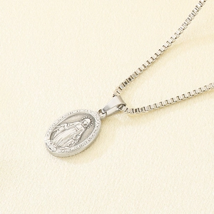 Macro detail of silver Virgin Mary oval medallion pendant on a sturdy box chain necklace