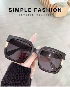 Detail of square black sunglasses showing the high-quality gold metal hinge and finish