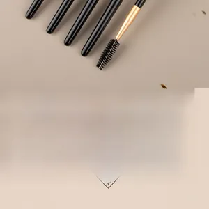 Detail of dual-ended eyebrow brushes with black matte handles and gold metal ferrules