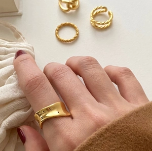 Detailed close-up of irregular wavy gold-plated sterling silver rings set on finger