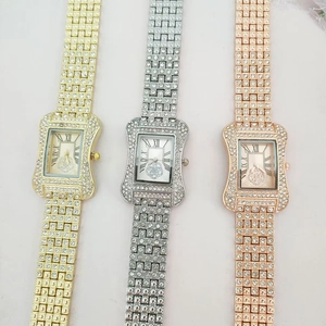 Close-up of three square diamond-encrusted watches in gold, silver, and rose gold finishes