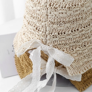 Detail view of hand-knitted bucket hats featuring delicate lace bows and woven textures