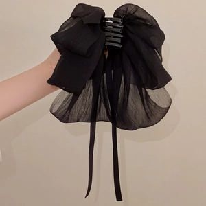 Detail of elegant black tulle bow hair claw with long ribbons for a delicate hairstyle