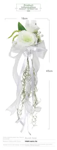 Detail of white silk wedding glass flower with satin ribbon and green leaf accents