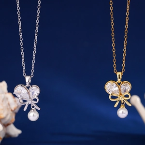 Elegant gold and silver bow necklaces with zircon and pearls on dark blue background