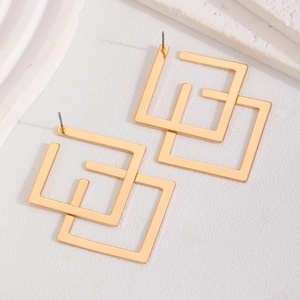 Minimalist gold geometric interlocking square stud earrings on a textured background