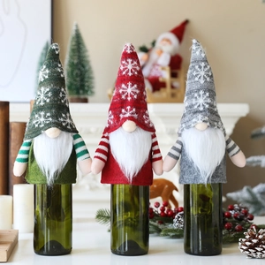 Three festive Christmas gnome wine bottle covers with knitted snowflake hats in red green grey