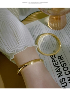 Detail of 18k gold plated titanium steel bangle with hammered texture and reflective finish