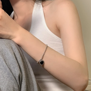Detail view of a vintage silver bead bracelet featuring a black heart-shaped pendant