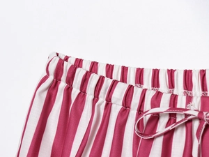 Detail of red and white striped pajama pants featuring elastic waist and adjustable drawstring